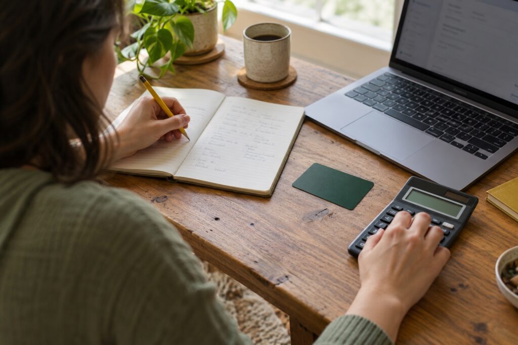 An adult comparing notes and using a calculator beside an unbranded card.